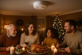 detector de humo en sala de casa con familia comiendo en la mesa un banquete de navidad